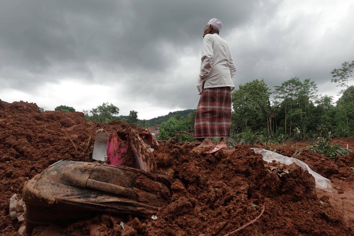 Warga melihat lokasi terdampak tanah longsor hingga menimbun rumah warga di Desa Cibeunying, Majenang, Cilacap, Jawa Tengah, Jumat (14/11/2025). (ANTARA FOTO/Idhad Zakaria)