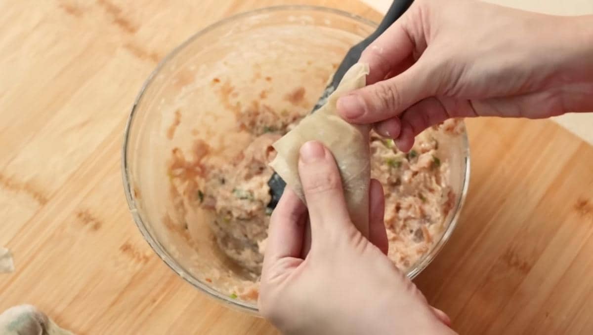 ilutrasi mengisi kulit pangsit dengan adonan ayam