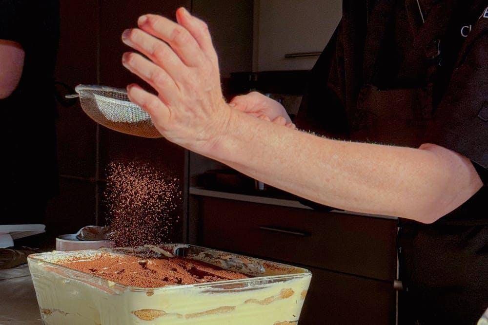 ilustrasi menaburi tiramisu dengan bubuk kakao