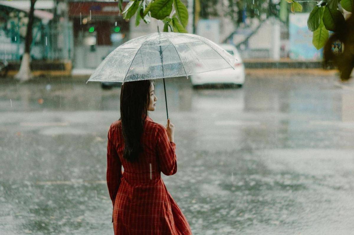 Seorang wanita sedang membawa payung hujan.