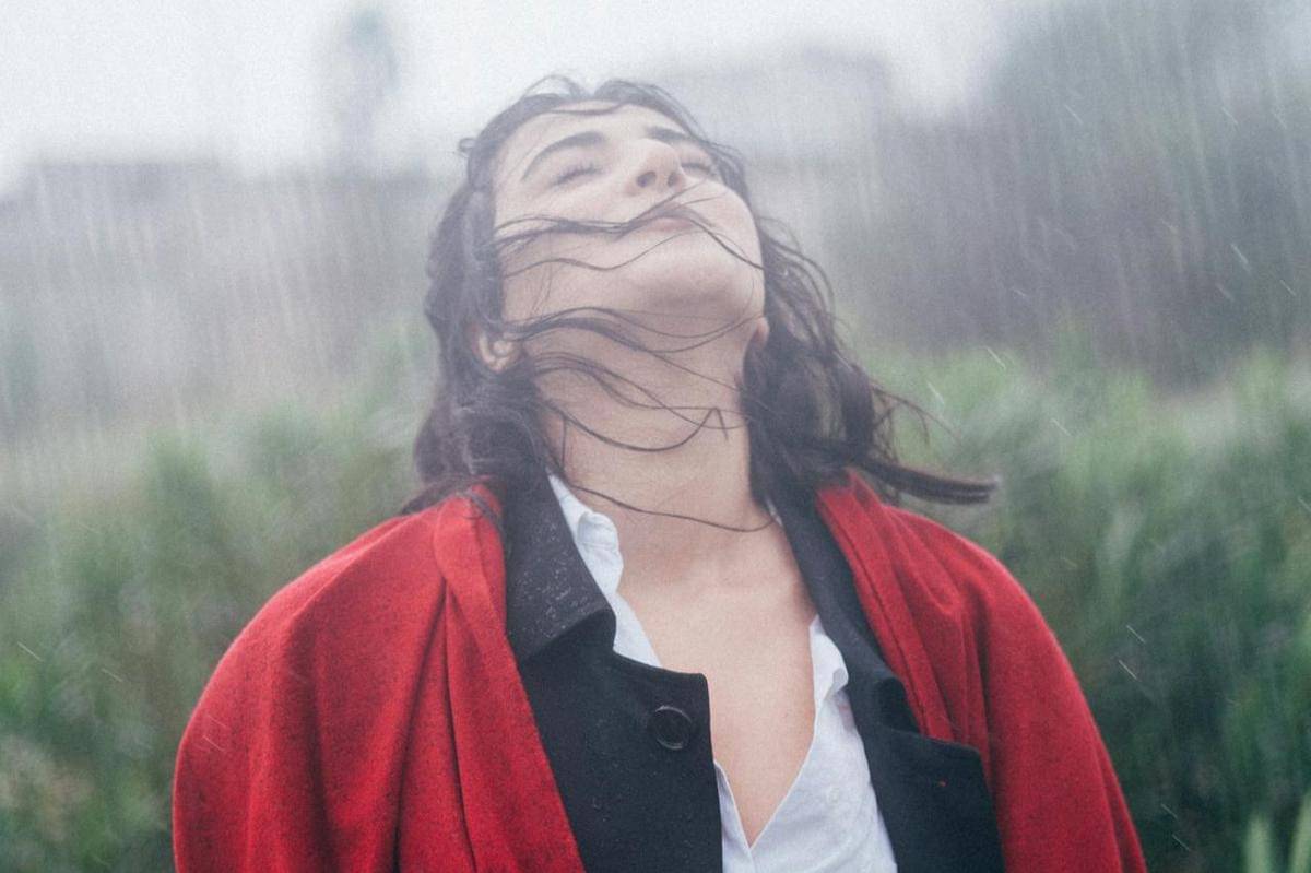 Seorang wanita sedang mandi hujan.