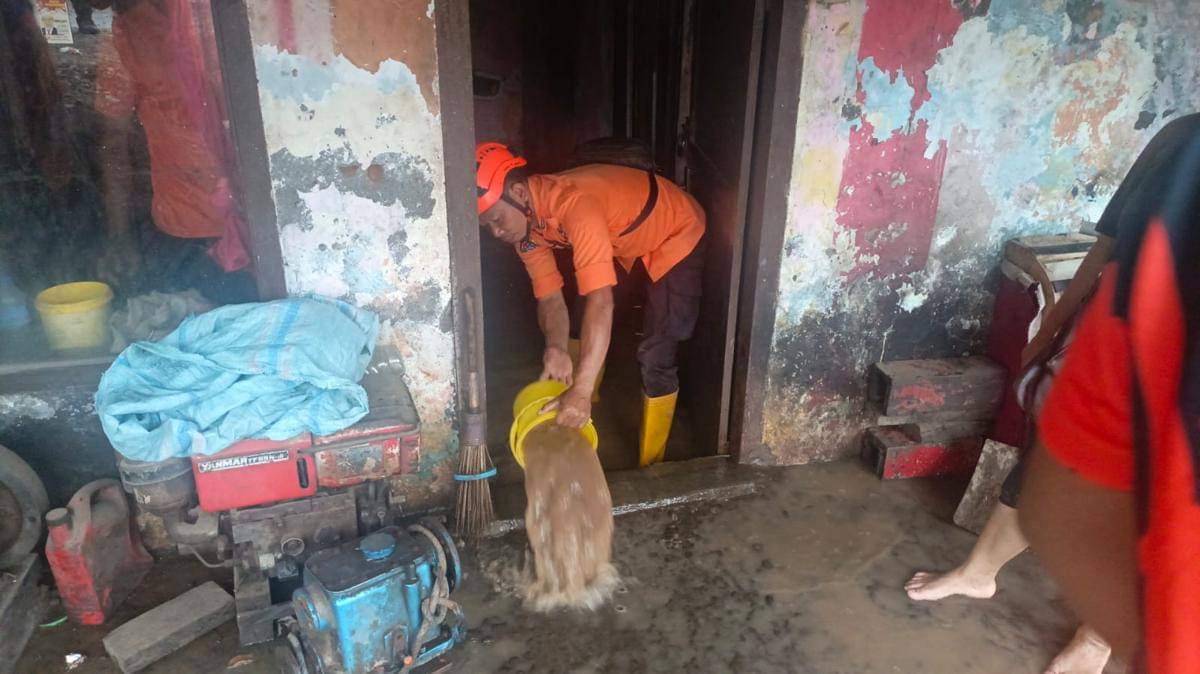 Petugas BPBD menyedot air yang merendam rumah warga.