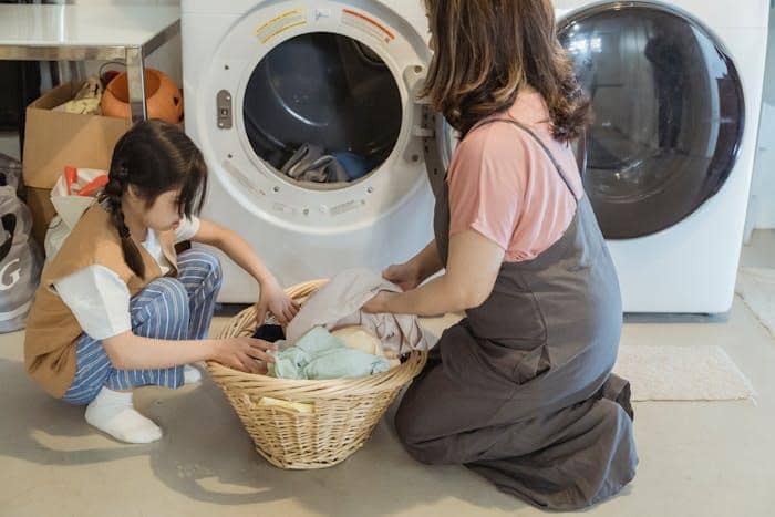Orang memasukkan pakaian ke mesin cuci
