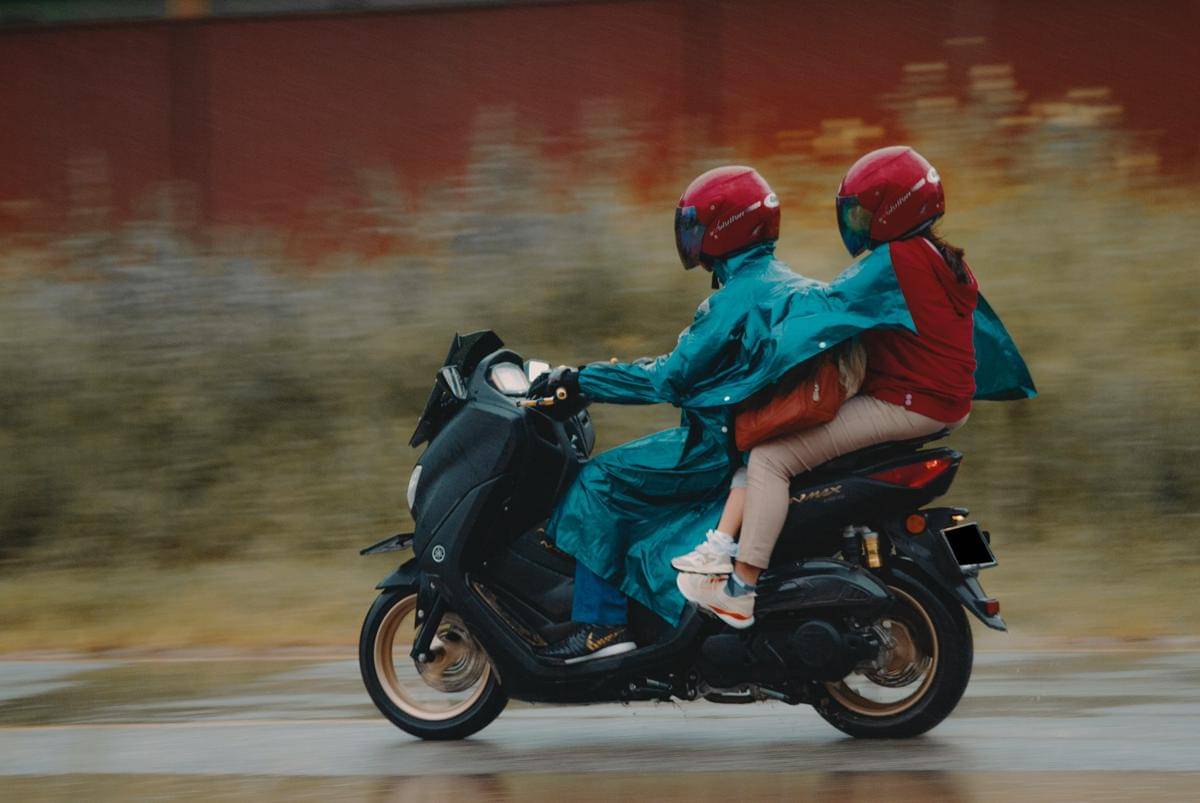 ilustrasi mengendarai motor dengan jas hujan
