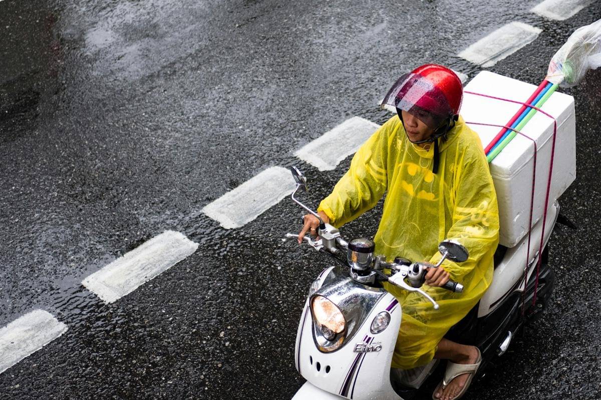 ilustrasi mengendarai motor dengan jas hujan