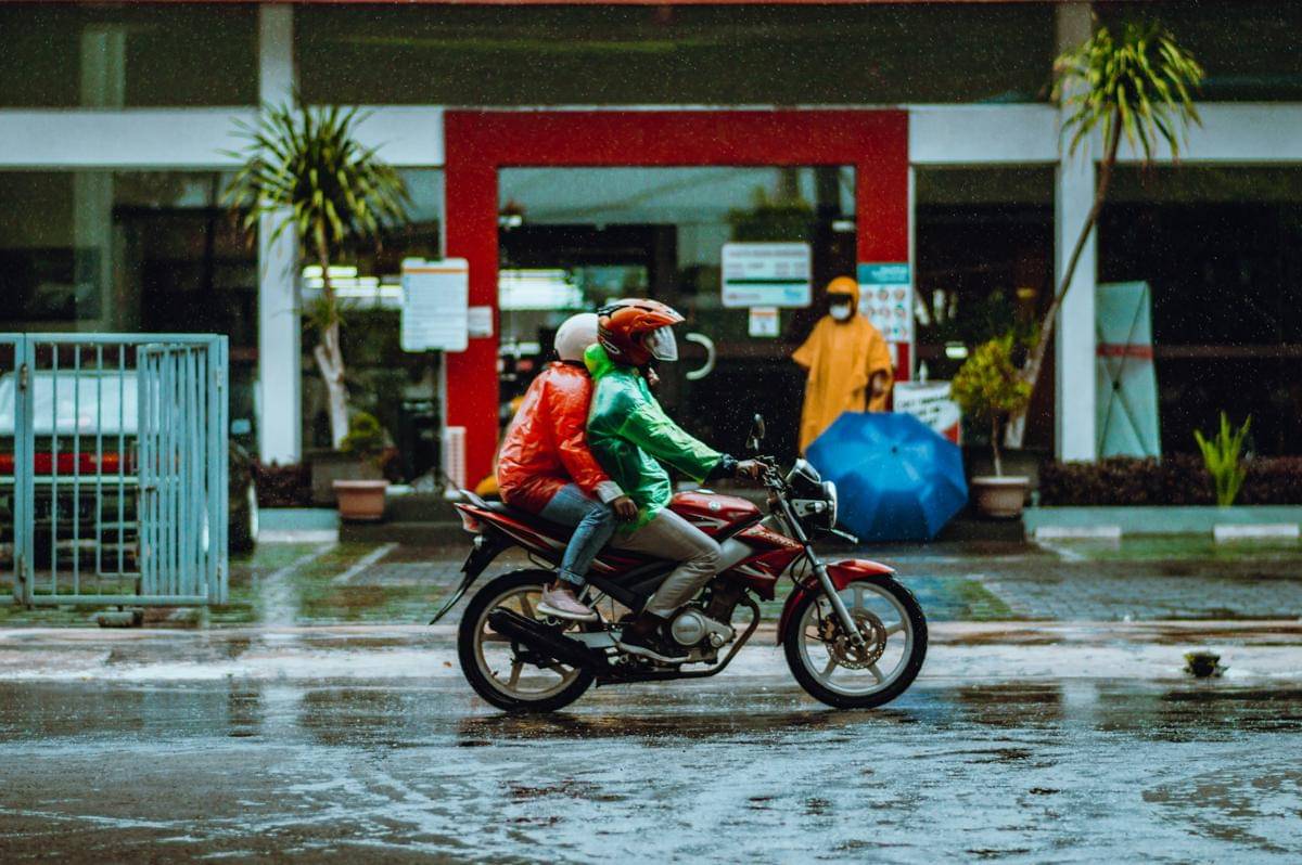 ilustrasi mengendarai motor dengan jas hujan