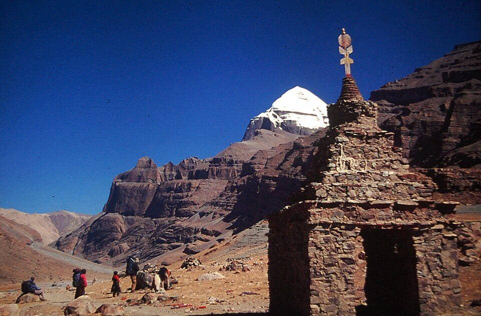Puncak Gunung Kailash yang megah menjadi latar bagi stupa dan para peziarah dalam perjalanan spiritual mereka.