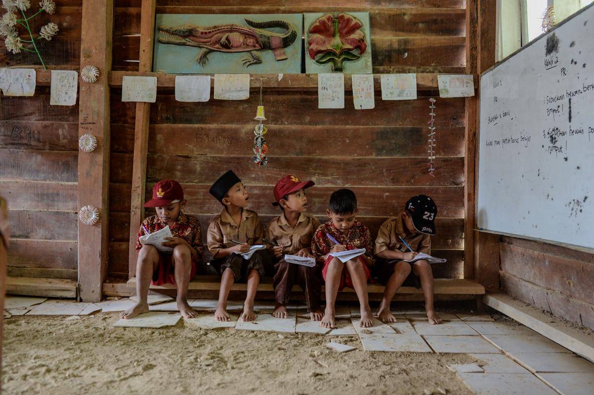 Sejumlah siswa kelas dua dan kelas satu mencatat PR saat mengikuti kegiatan belajar mengajar di SD Negeri 2 Sorongan kelas jauh Batu Payung, Cibaliung, Pandeglang, Banten, Kamis (20/11/2025). Sebanyak 23 siswa dan satu guru yang mengajar di daerah terpencil Kabupaten Pandeglang tersebut hanya memiliki satu ruang belajar yang rusak parah untuk menampung siswa dari kelas satu hingga enam. ANTARA FOTO/Muhammad Bagus Khoirunas