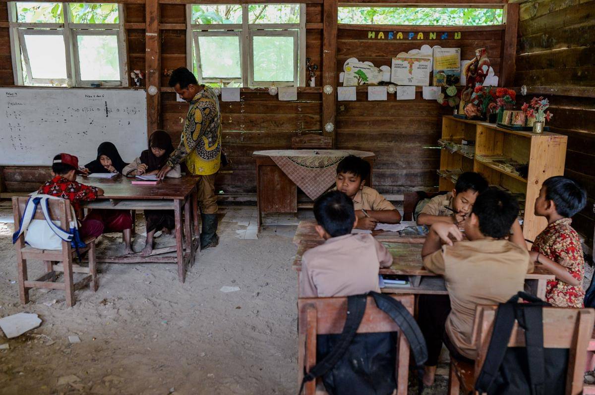 Guru Armani memeriksa tugas pembelajaran siswa di SD Negeri 2 Sorongan kelas jauh Batu Payung, Cibaliung, Pandeglang, Banten, Kamis (20/11/2025). Sebanyak 23 siswa dan satu guru yang mengajar di daerah terpencil Kabupaten Pandeglang tersebut hanya memiliki satu ruang belajar yang rusak parah untuk menampung siswa dari kelas satu hingga enam. ANTARA FOTO/Muhammad Bagus Khoirunas