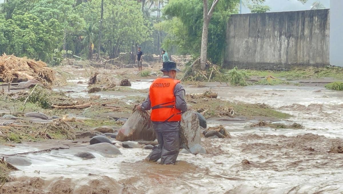 Seorang personel Brimob membantu warga mengangkat barangnya di Lubuk Minturun Padang.