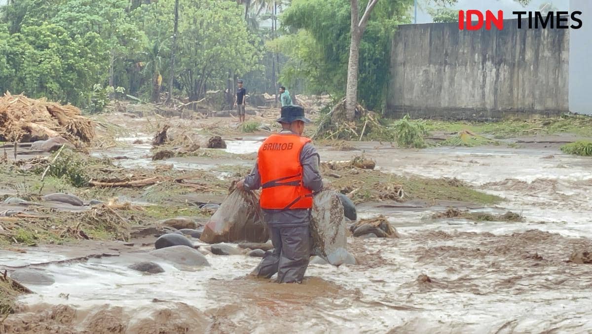 Seorang personel Brimob membantu warga mengangkat barangnya di Lubuk Minturun Padang.