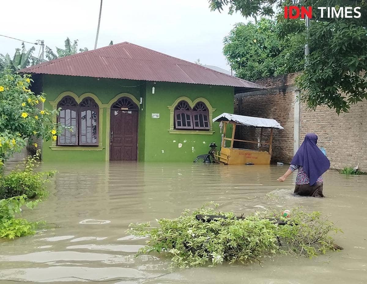 Sunarsih saat menuju ke rumahnya yang terendam banjir (IDN Times/Eko Agus Herianto)