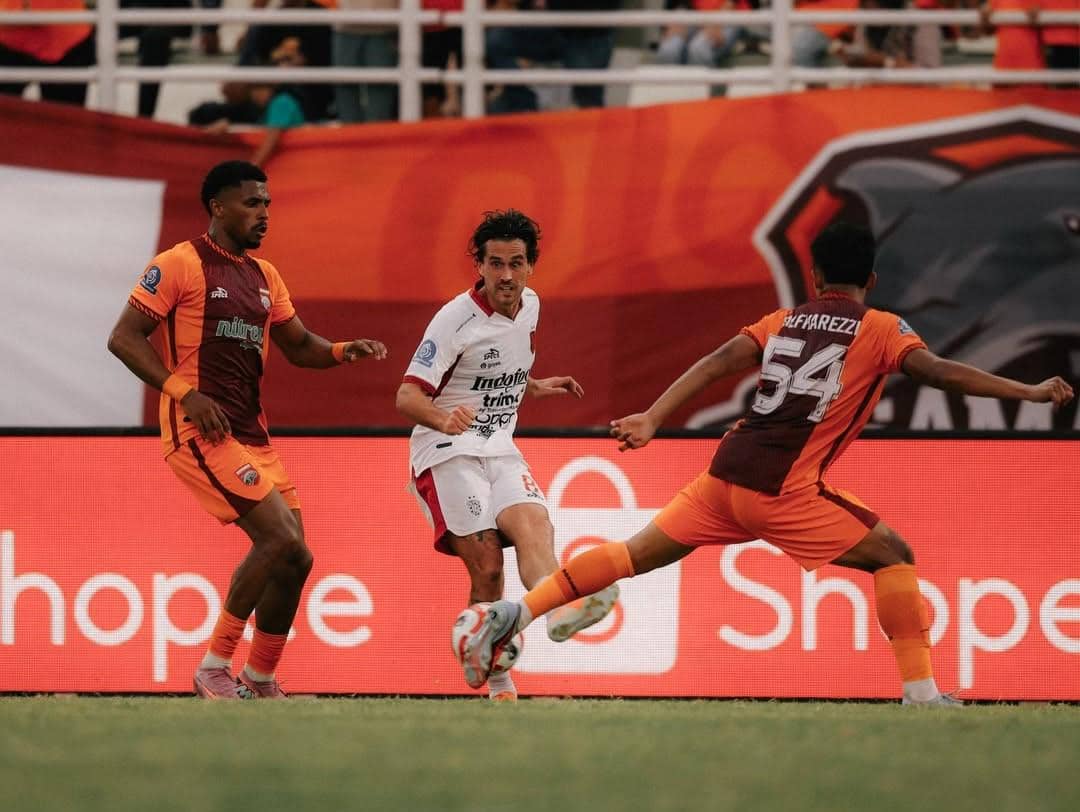 Pemain Bali United (putih) diapit oleh dua pemain Borneo FC. 