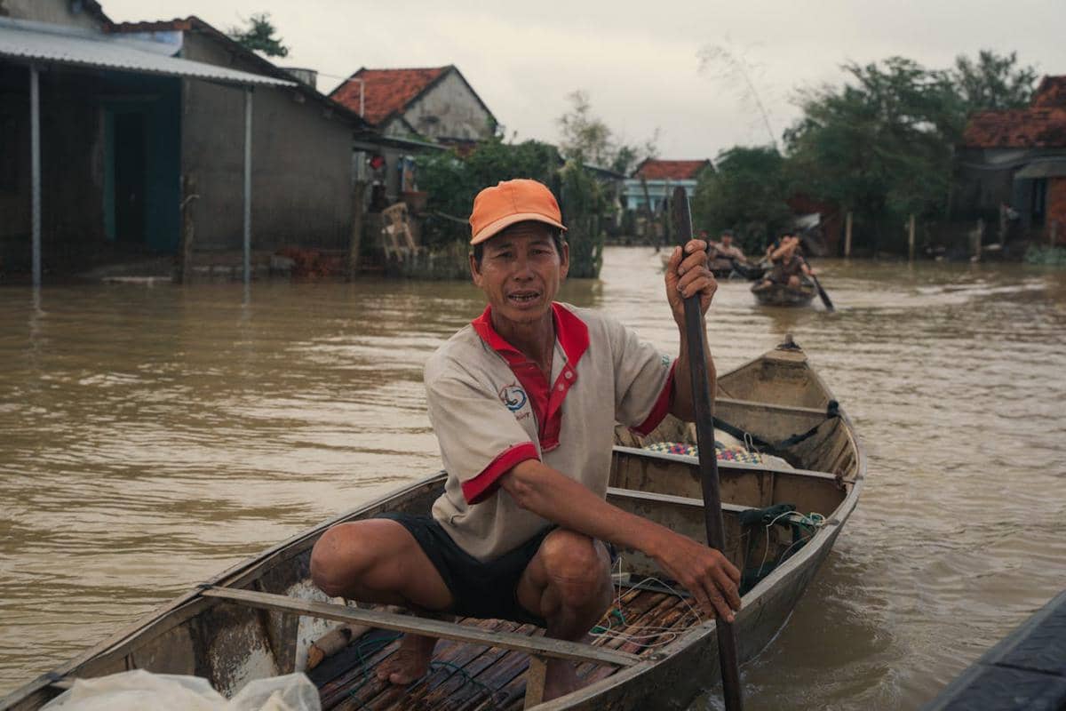 ilustrasi seorang pria yang sedang mendayung perahu saat terjadi banjir