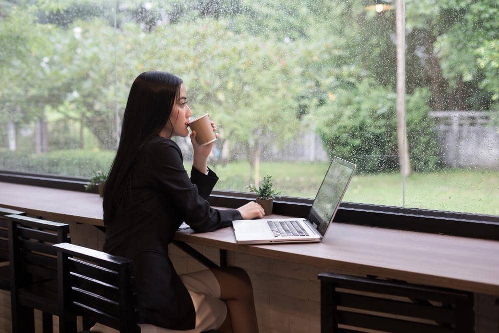 Ilustrasi seorang perempuan yang duduk di depan laptop, dengan fokus pada penggunaan perangkat komputer pribadi.