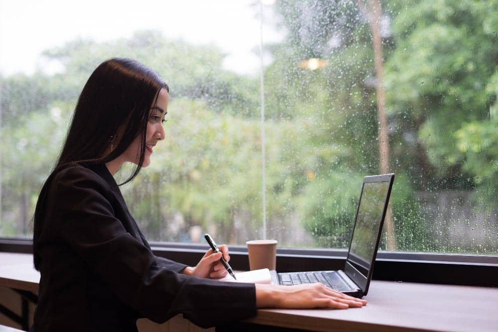 Perempuan duduk di depan laptop