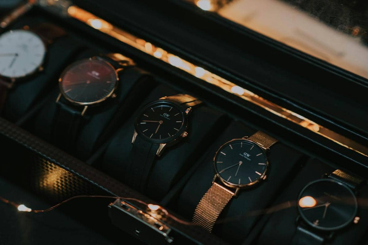 Beberapa jam tangan elegan dengan tali kulit dan logam tersusun rapi di dalam kotak penyimpanan berwarna gelap.