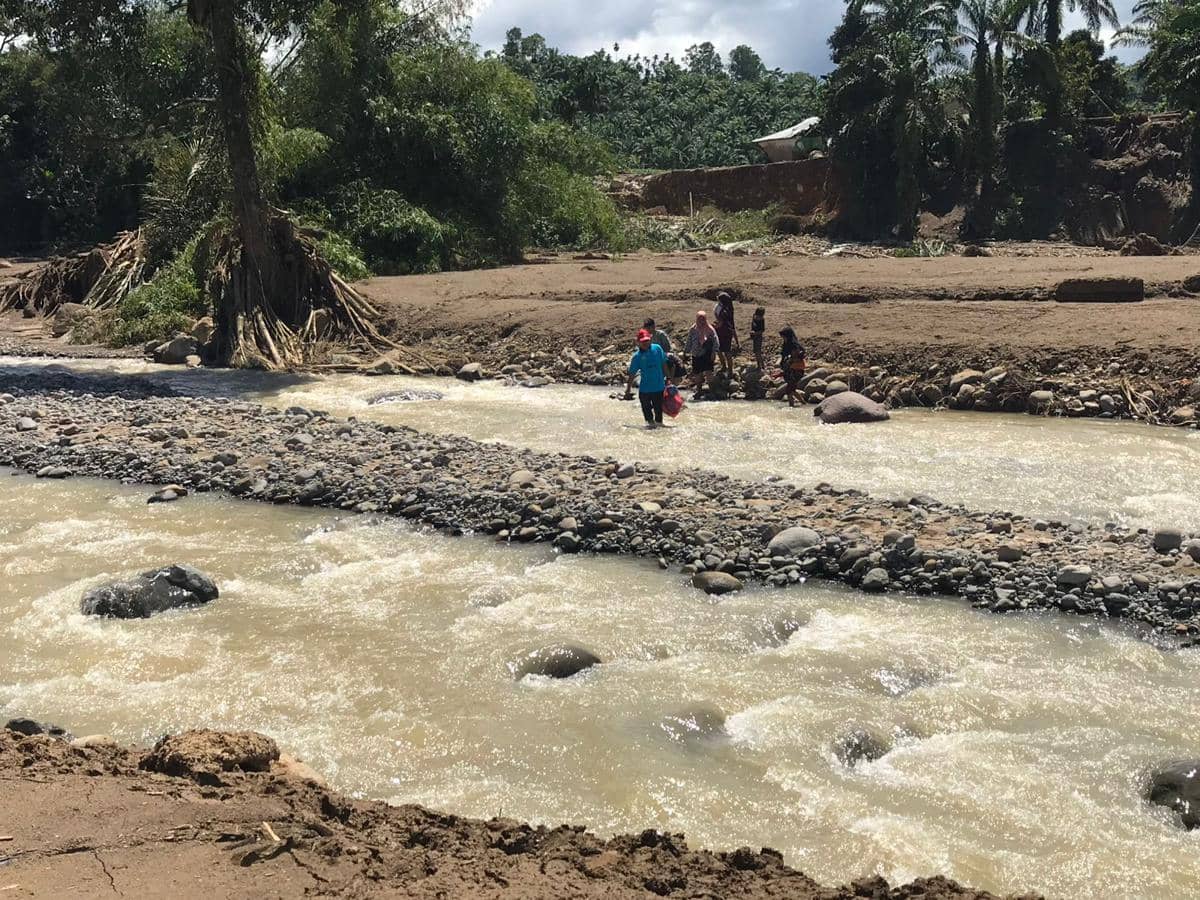 Warga menyeberangi Sungai Batang Nanggang yang meluap saat banjir bandang di Palembayan, Kabupaten Agam, Kamis (27/11/2025).