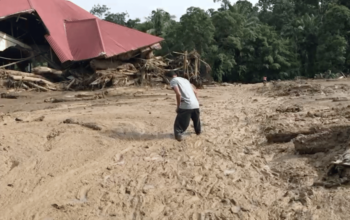 Seorang warga melintasi endapan lumpur usai banjir bandang untuk membantu proses evakuasi di Palembang, Kabupaten Agam. 