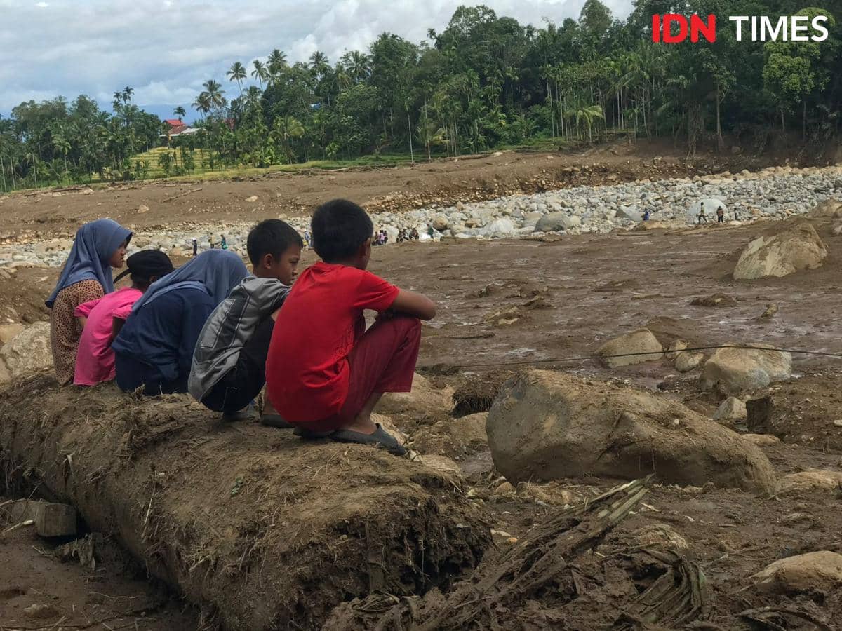 Sekelompok anak sedang memandang ke arah Sungai Batang Nanggang yang meluap saat banjir bandang di Palembayan, Kabupaten Agam, Kamis (27/11/2025).