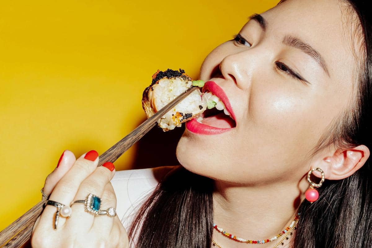 perempuan dengan lipstik makan sushi 