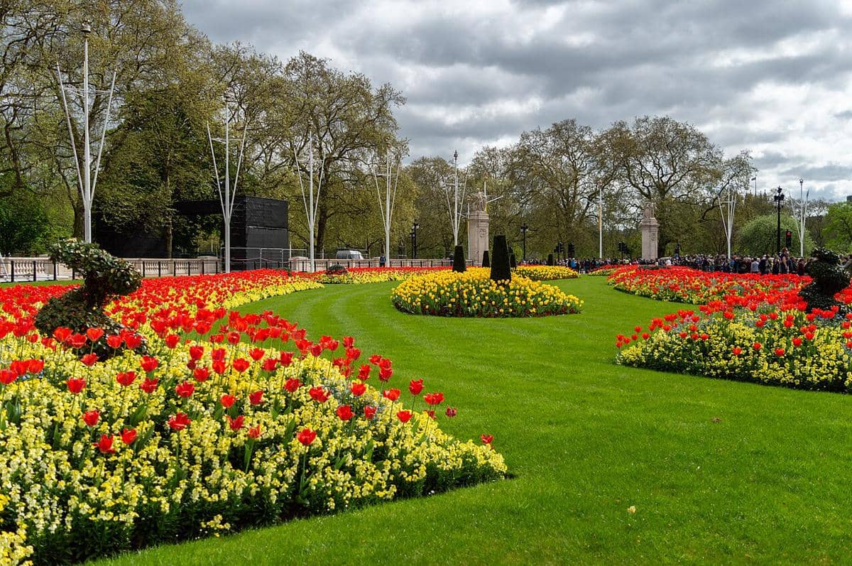 Hamparan bunga dan taman formal di bagian depan Istana Buckingham di London, Inggris. Area ini juga dikenal sebagai Taman Memorial, yang dibuat pada tahun 1901 sebagai bagian dari keseluruhan desain monumen peringatan untuk Ratu Victoria