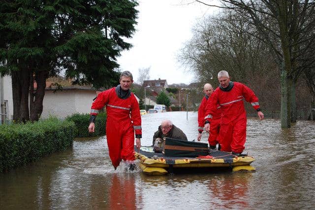 ilustrasi petugas membantu lansia dari arus banjir