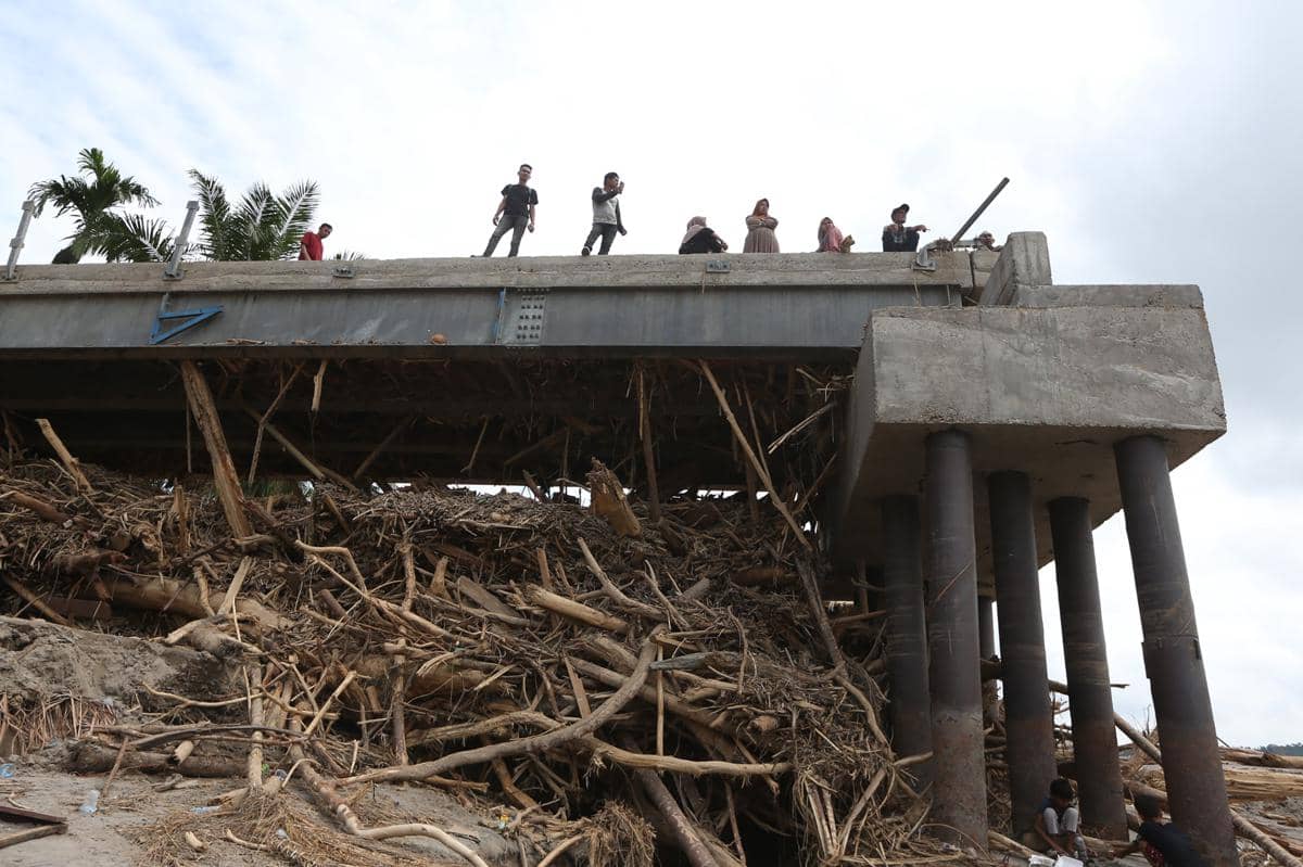 Warga berada di atas jembatan yang putus akibat bencana banjir dan luapan Sungai Peusangan di Peusangan Selatan, Bireuen, Aceh, Rabu (3/12/2025). Pemerintah Aceh telah menetapkan status darurat bencana hidrometeorologi selama 14 hari sejak 28 November hingga 11 Desember pascabencana banjir dan longsor yang terjadi di 16 kabupaten/kota (ANTARA FOTO/Irwansyah Putra)