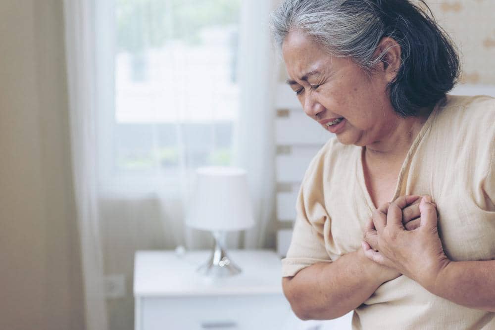 Senior female asian suffering from bad pain in her chest heart attack at home