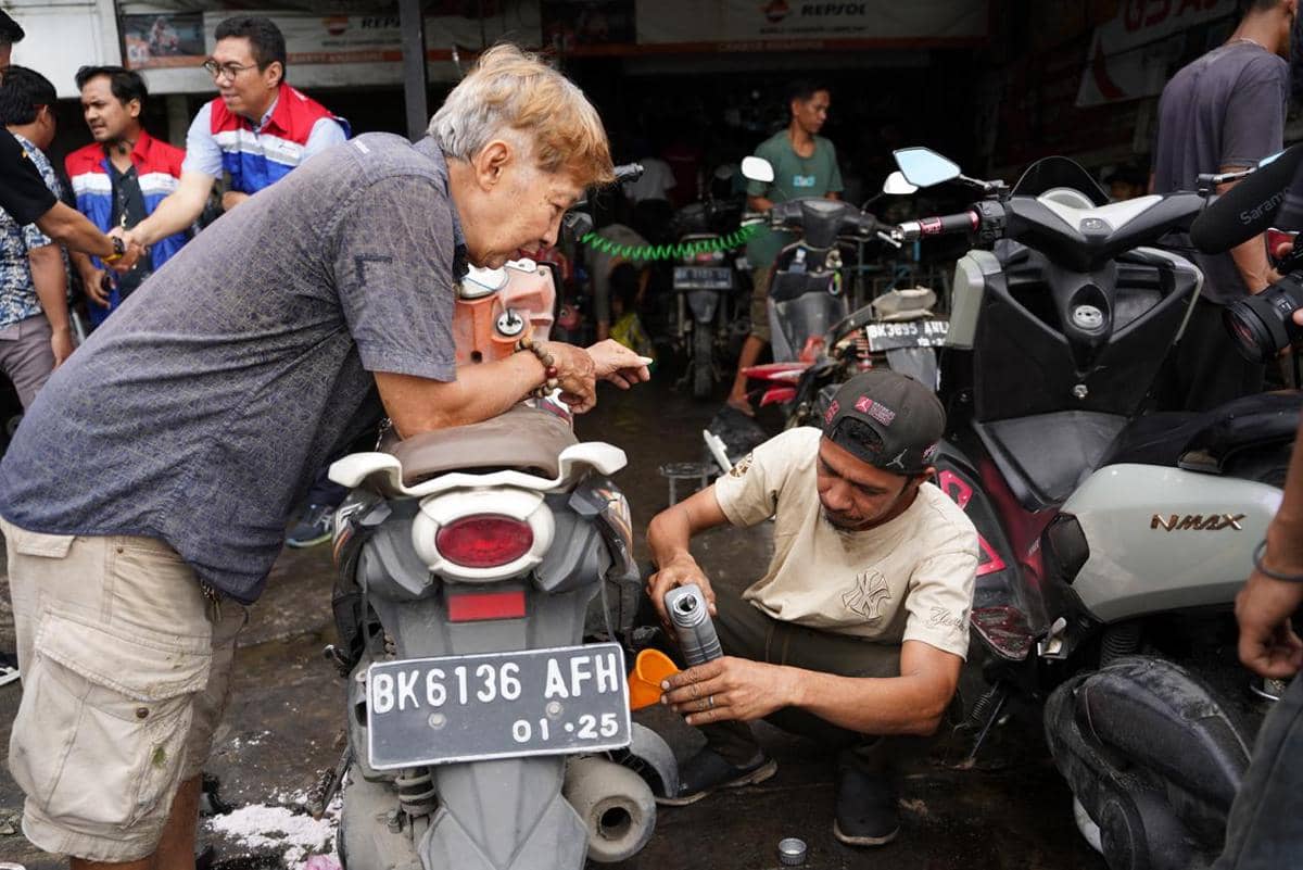 Mekanik bengkel melakukan penggantian oli pada motor yang terendam banjir di Medan untuk mencegah kerusakan mesin lanjutan.jpeg