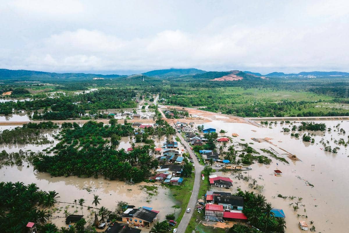 Aerial view of a flooded village with houses and roads submerged after heavy rain.