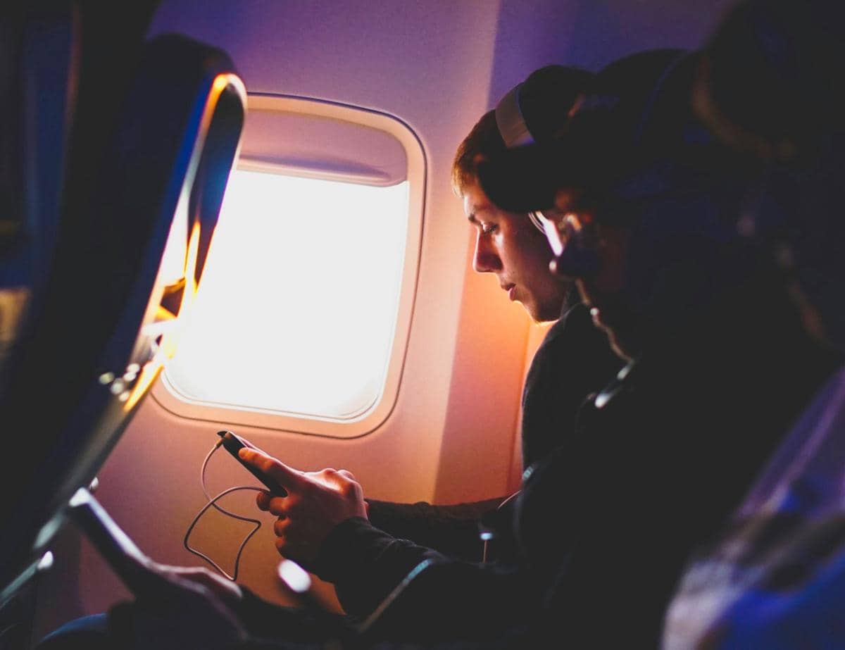 ilustrasi penumpang pesawat sedang mendengarkan musik