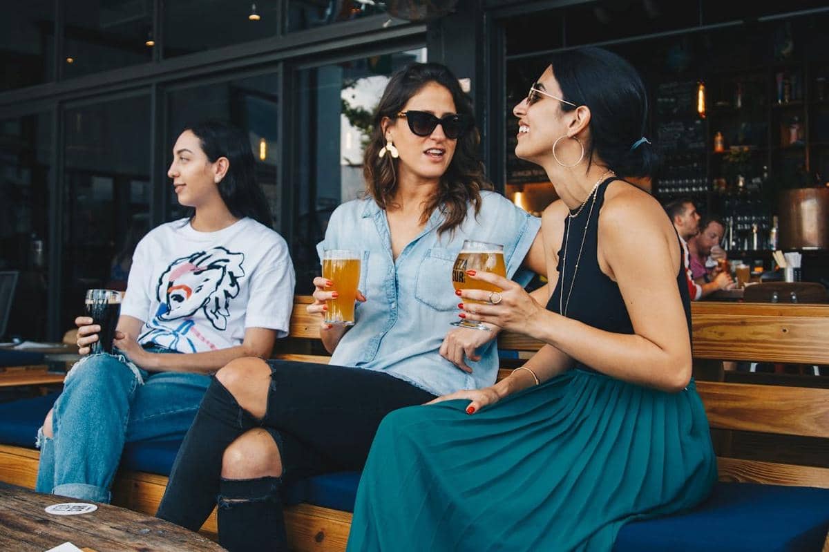 Tiga orang wanita sedang ngopi di cafe.