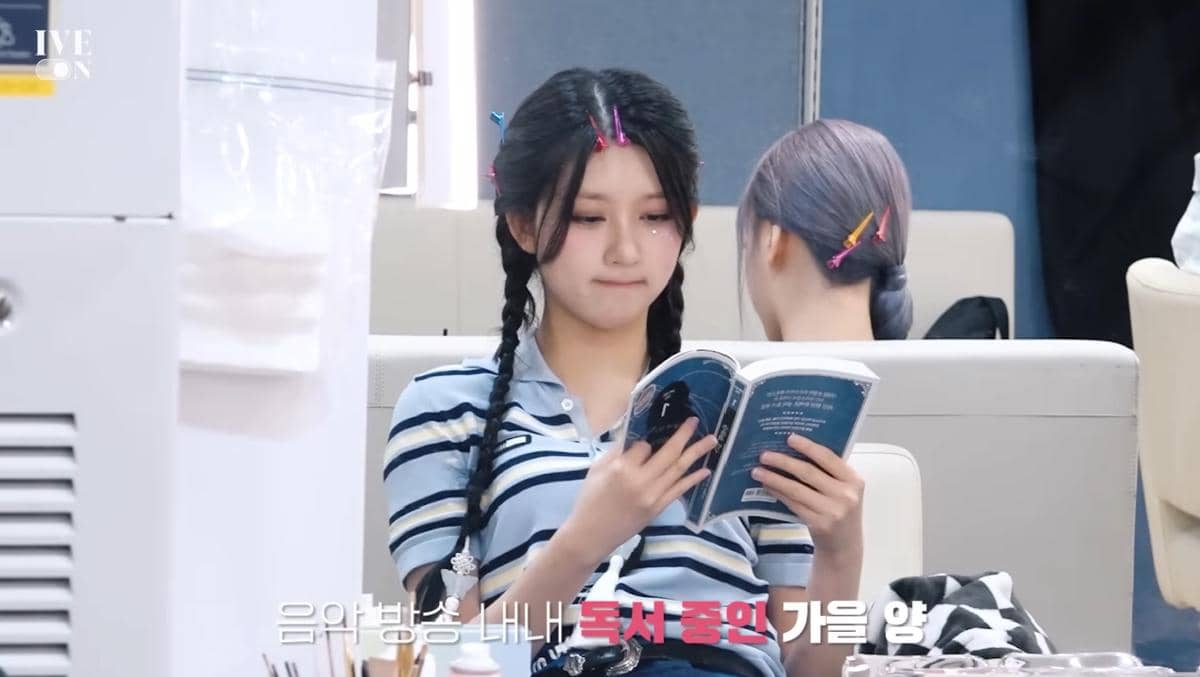Gaeul IVE tertangkap kamera sedang membaca buku di ruang make up sebelum tampil di music show