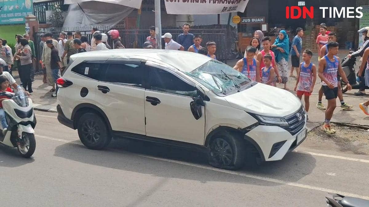 Warga tampak membantu mobil yang terbalik di Jl AP Pettarani Makassar, Senin (8/12/2025). IDN Times/Darsil Yahya