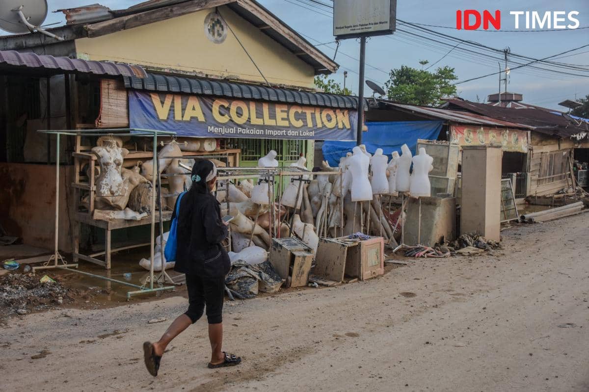 Seorang warga berjalan melintasi tu​mpukan manekin di kawasan Kecamatan Rantau Panjang, Kabupaten Aceh Tamiang, Minggu (7/12/2025). (IDN Times/Prayugo Utomo)