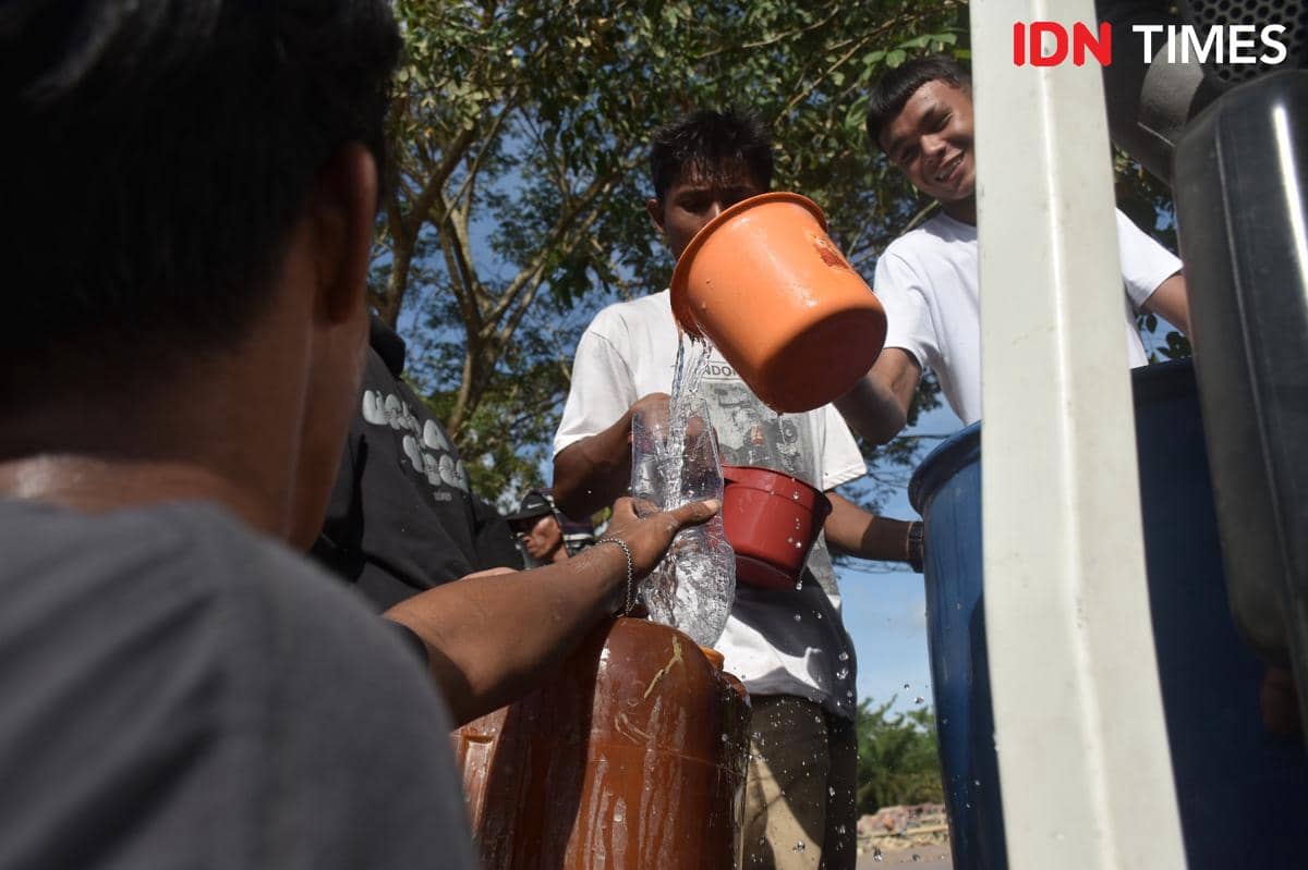 Warga Aceh Tamiang saling membantu memberi air bersih, Minggu (7/12/2025) (IDN Times/Prayugo Utomo)
