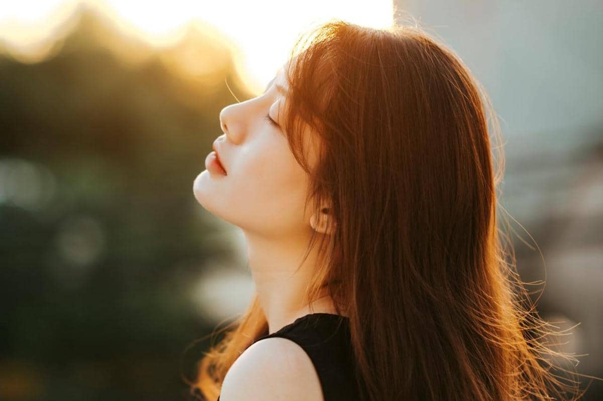 Wanita sedang menikmati sinar matahari pagi.