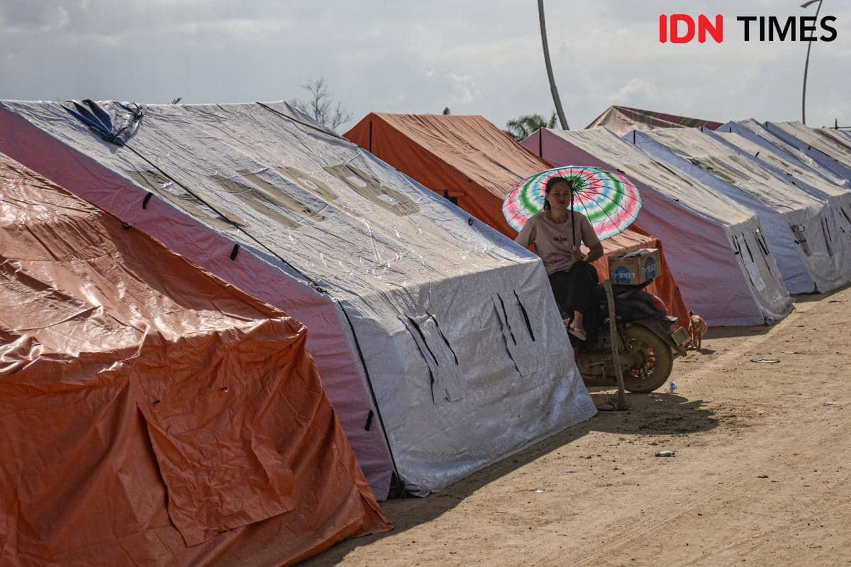 Gabriel, penyintas banjir Aceh Tamiang duduk di depan tenda pengungsian di kawasan jembatan Sungai Tamiang, Kecamatan Kuala Simpang, Kamis (11/12/2025). (IDN Times/Prayugo Utomo)
