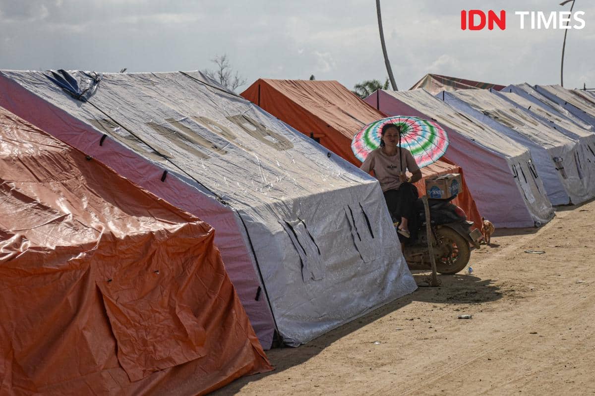 Gabriel, penyintas banjir Aceh Tamiang duduk di depan tenda pengungsian di kawasan jembatan Sungai Tamiang, Kecamatan Kuala Simpang, Kamis (11/12/2025). (IDN Times/Prayugo Utomo)