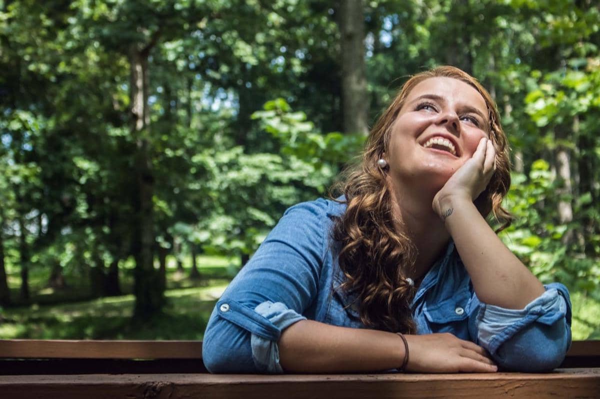Wanita di alam sedang duduk di kursi.
