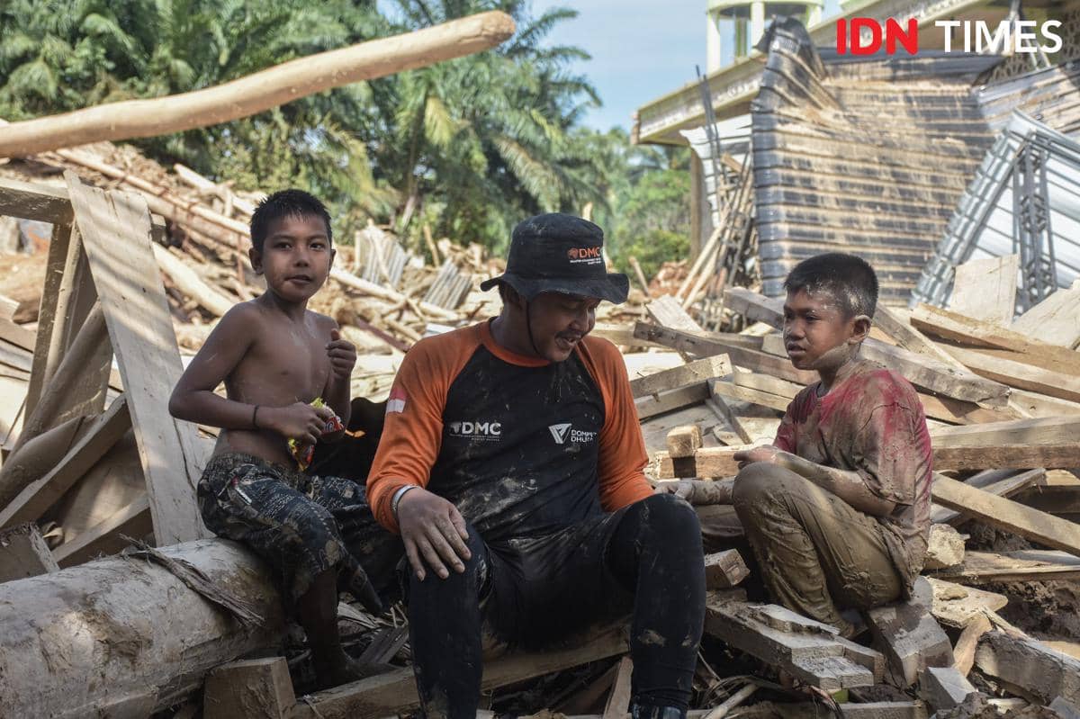 Relawam Disaster Management Center (DMC) Dompet Dhuafa berbincang dengan anak-anak di Desa Sekumur, Kecamatan Sekerak, Kabupaten Aceh Tamiang, Aceh, Kamis (11/12/2025). (IDN Times/Prayugo Utomo)