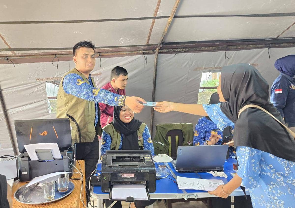 Seorang petugas Disdukcapil Padang memberikan KTP warga terdampak bencana di Huntara (Foto: Diskominfo Padang)