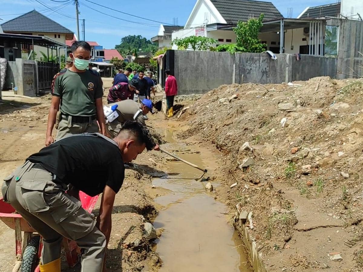 Personel Satpol PP Padang membantu warga membersihkan sisa lumpur banjir bandang di pemukiman warga Kota Padang