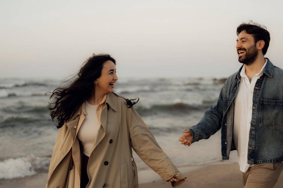 ilustrasi wanita dan pria tertawa bersama di tepi pantai