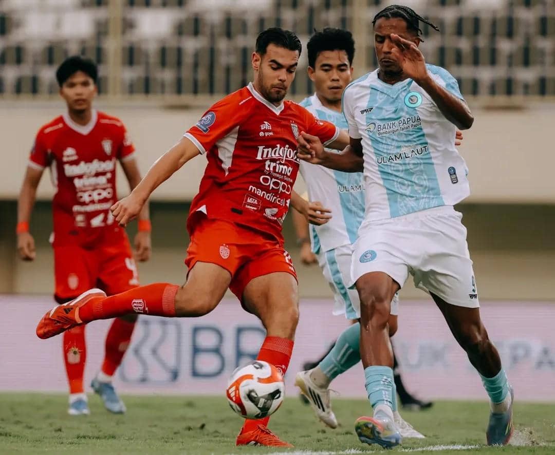 Pemain Bali United (merah) dihadang pemain PSBS Biak (putih). 