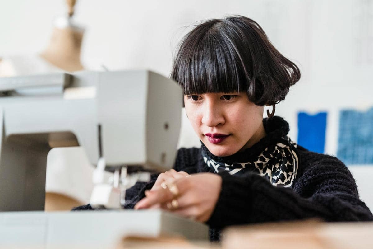 Ilustrasi orang yang sedang menjahit sebagai kegiatan kelola stres.