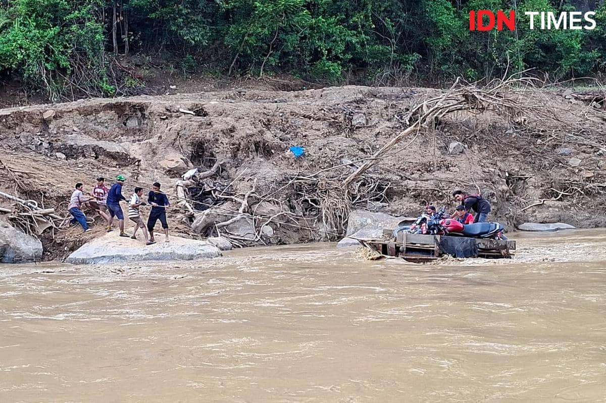 Warga Mukim Jamat menyeberang menggunakan getek karena jembatan darurat putus (IDN Times/Muhammad Saifullah)