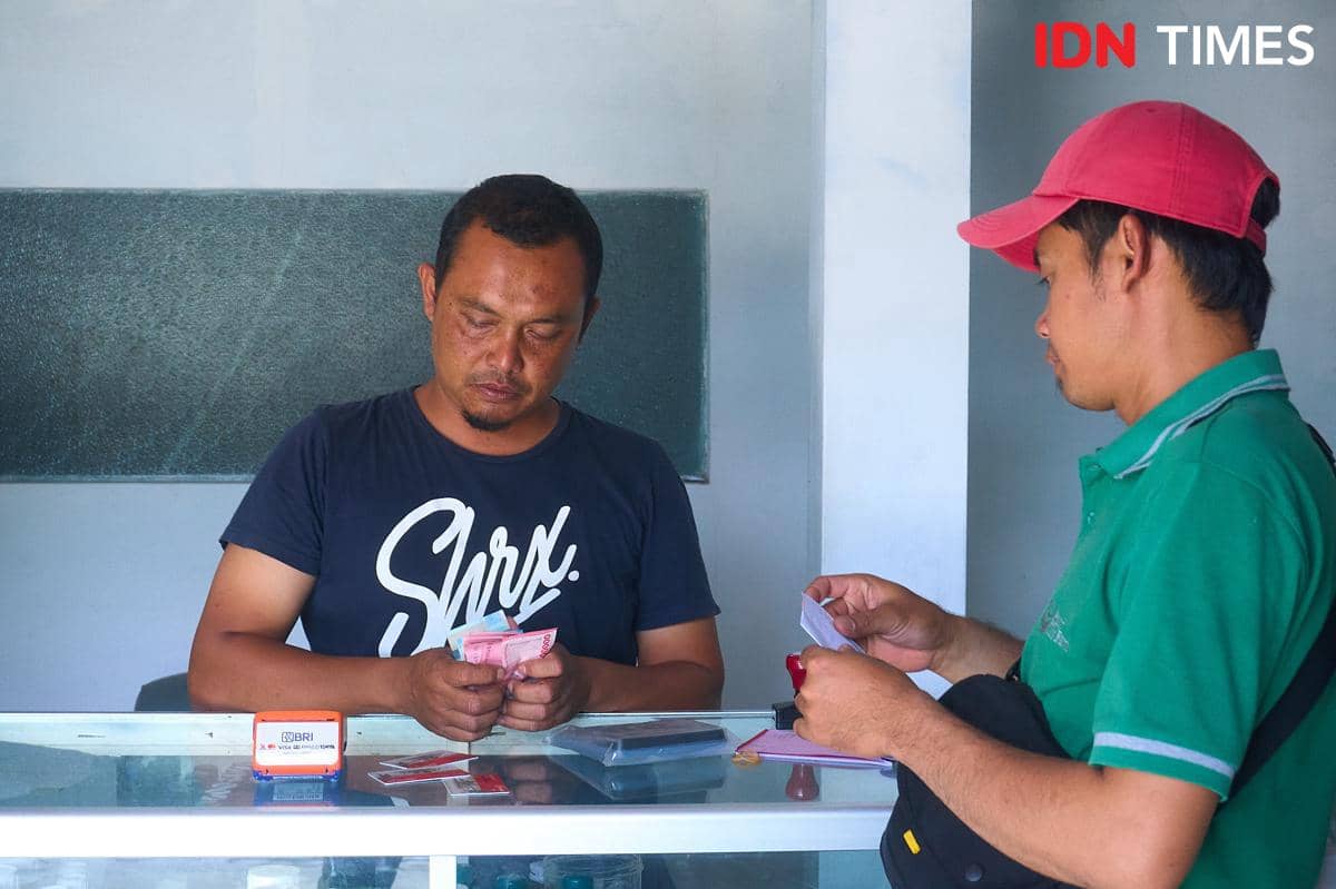 Bendahara Kelompok Tani Maju Mulyo, Muhammad Amanullah (kanan) menebus pupuk bersubsidi di kios Penerima Pupuk pada Titik Serah (PPTS) UD Jambul di Desa Pucang, Secang, Kabupaten Magelang, Senin (22/12/2025). (IDN Times/Dhana Kencana)