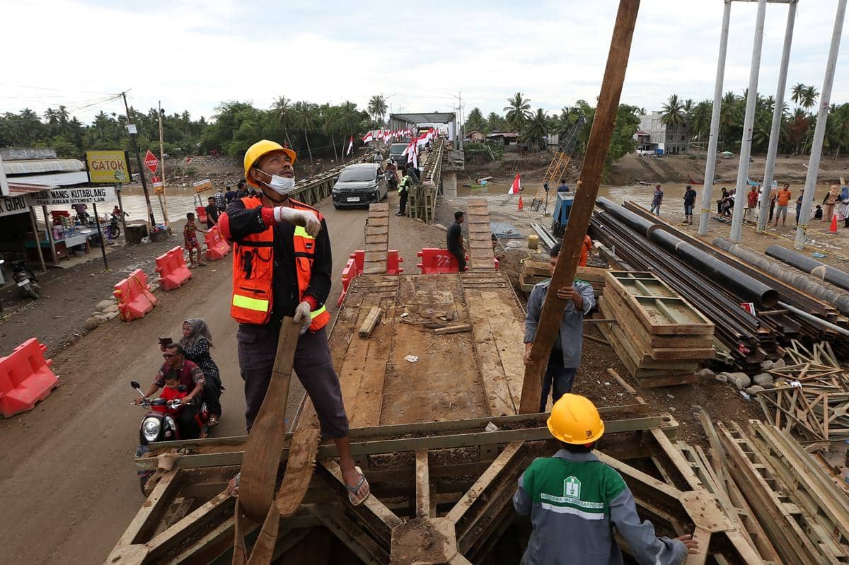 Warga dan kendaraan melewati jembatan darurat bailey Krueng Tingkeum yang baru selesai dibangun di Kuta Blang, Bireuen, Aceh, Sabtu (27/12/2025). Pemerintah bersama TNI/Polri telah menyelesaikan jembatan bailey Krueng Tingkeum, Kuta Blang (ANTARA FOTO/Irwansyah Putra)